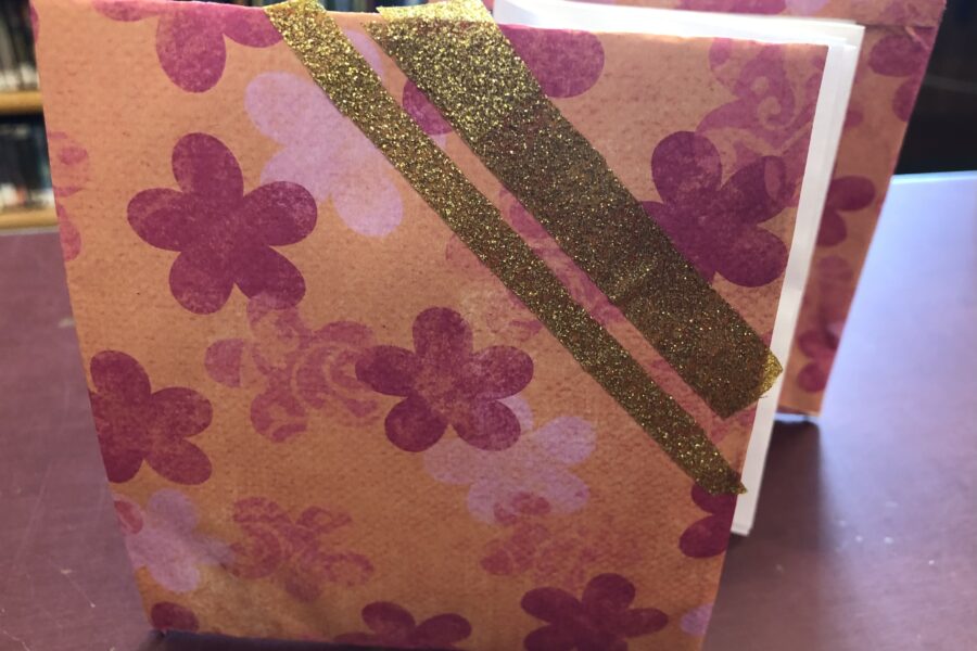 Image of a pink and orange accordion style notebook with gold accents.