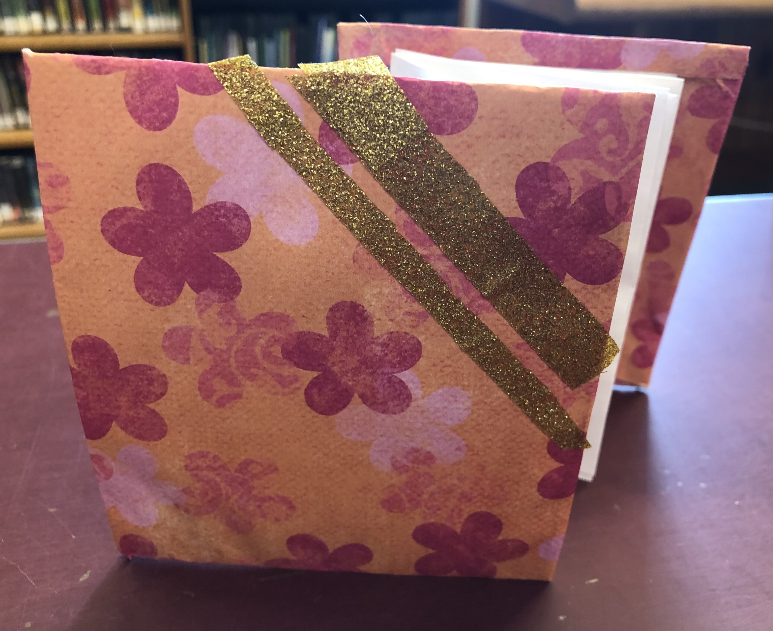 Image of a pink and orange accordion style notebook with gold accents.