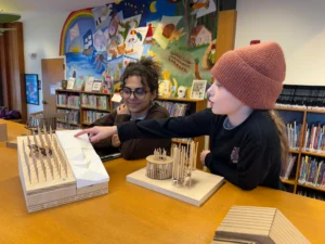 Pictured: Quincy discusses a model play structure created by the class for initial research with Norwich student Riyam Al-Janabi. The class attended our weekly Builders afternoon program to gather thoughts and ideas from young patrons.