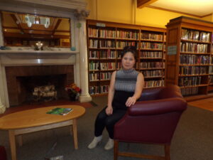 Artist Mun Ward sitting on a burgundy chair in front of the fireplace in the Kellogg-Hubbard Library