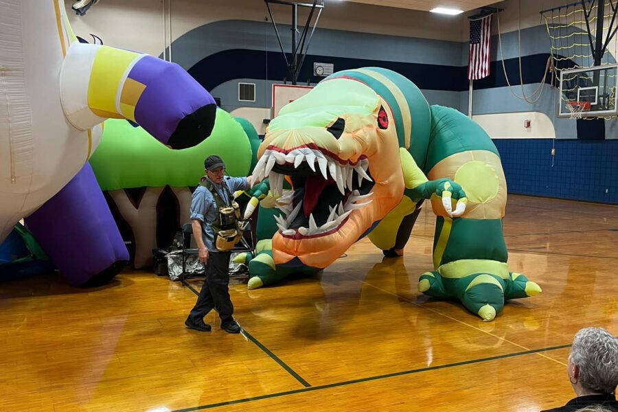 Man standing in front of large inflatable dinosaurs