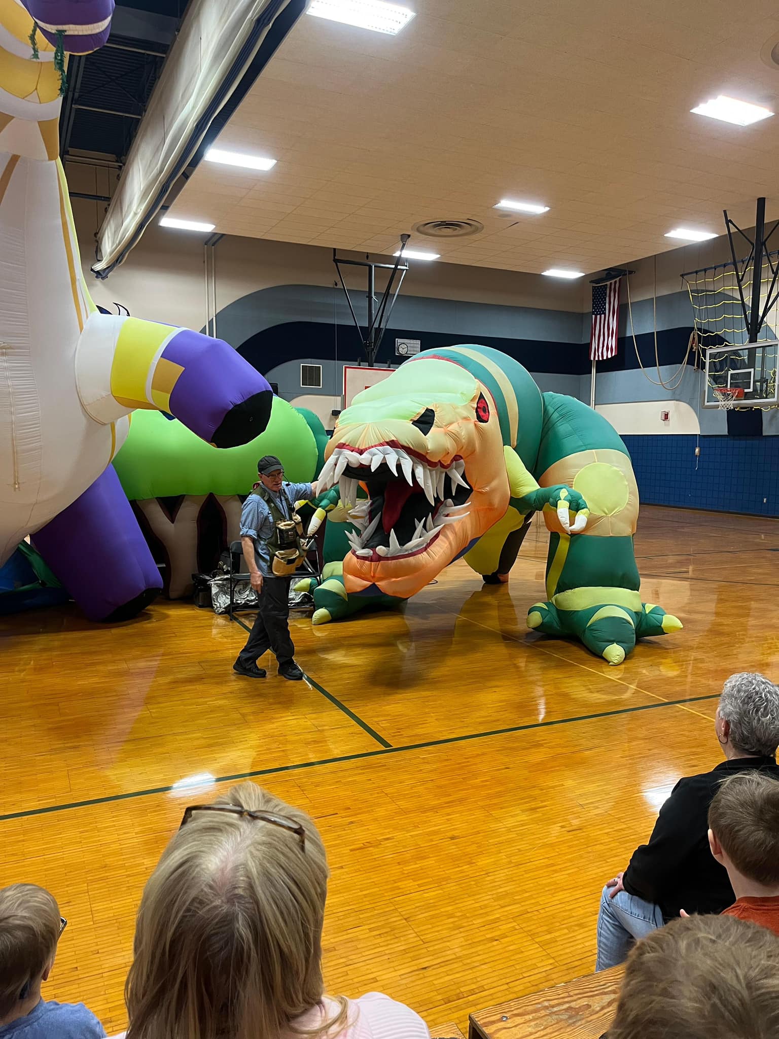 Man standing in front of large inflatable dinosaurs